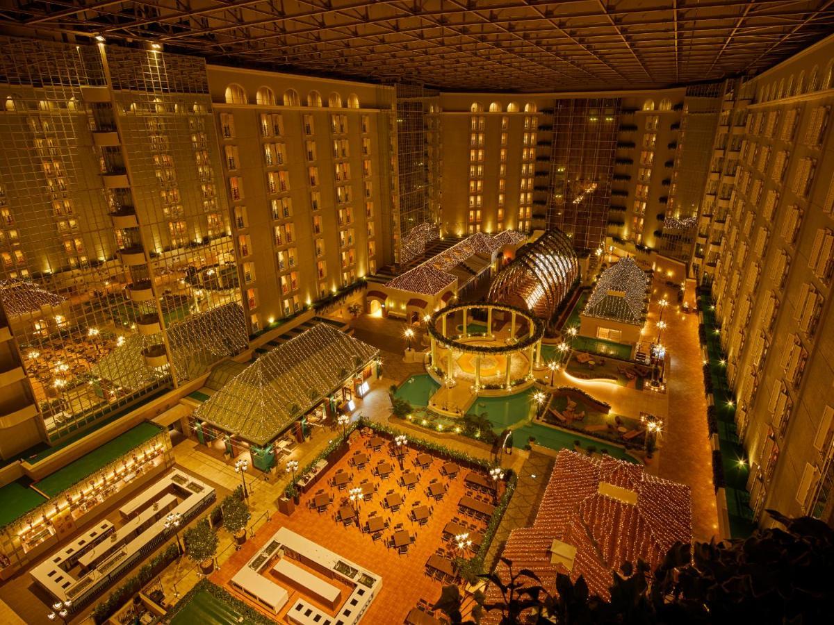 Готель Grand Nikko Tokyo Bay Maihama Urayasu Екстер'єр фото The photo shows a large, illuminated atrium of a hotel or resort complex. Several floors of what appear to be guest rooms or apartments surround the central area. The atrium contains a variety of amenities, including a pool or water feature, landscap