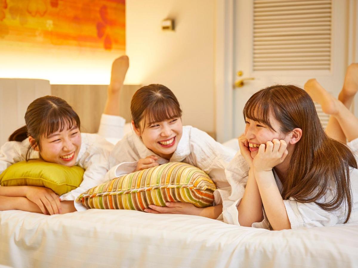 Готель Grand Nikko Tokyo Bay Maihama Urayasu Екстер'єр фото The photo shows three young women lounging together in a cozy indoor setting. They are dressed in white robes and appear to be relaxed and enjoying each other's company. The women are lying on a bed, with two of them resting on their arms and the thi