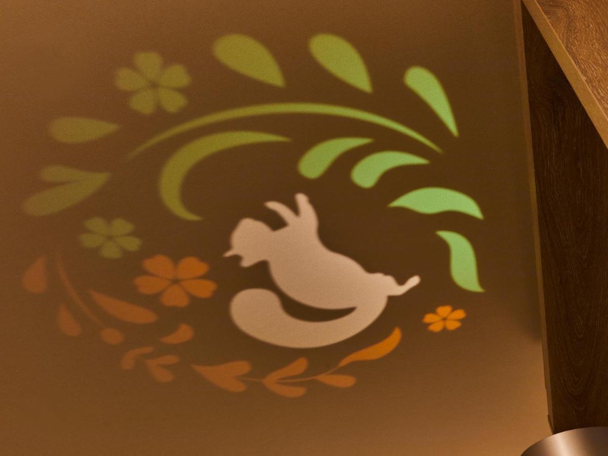 Готель Grand Nikko Tokyo Bay Maihama Urayasu Екстер'єр фото The photo shows a colorful projection on a surface that includes a playful illustration. The design features a white silhouette of a squirrel in a lively pose, surrounded by decorative elements like green leaves and flowers in shades of orange and ye