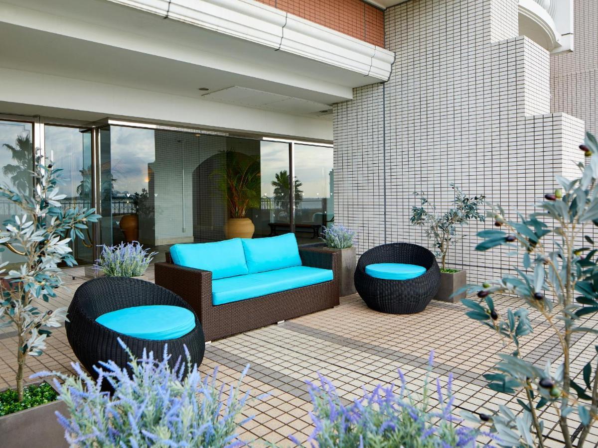 Готель Grand Nikko Tokyo Bay Maihama Urayasu Екстер'єр фото The image shows a stylish outdoor seating area. There is a brown couch with turquoise cushions, complemented by two matching round chairs nearby. The seating is arranged on a tiled patio, which is bordered by planters featuring lavender flowers and g