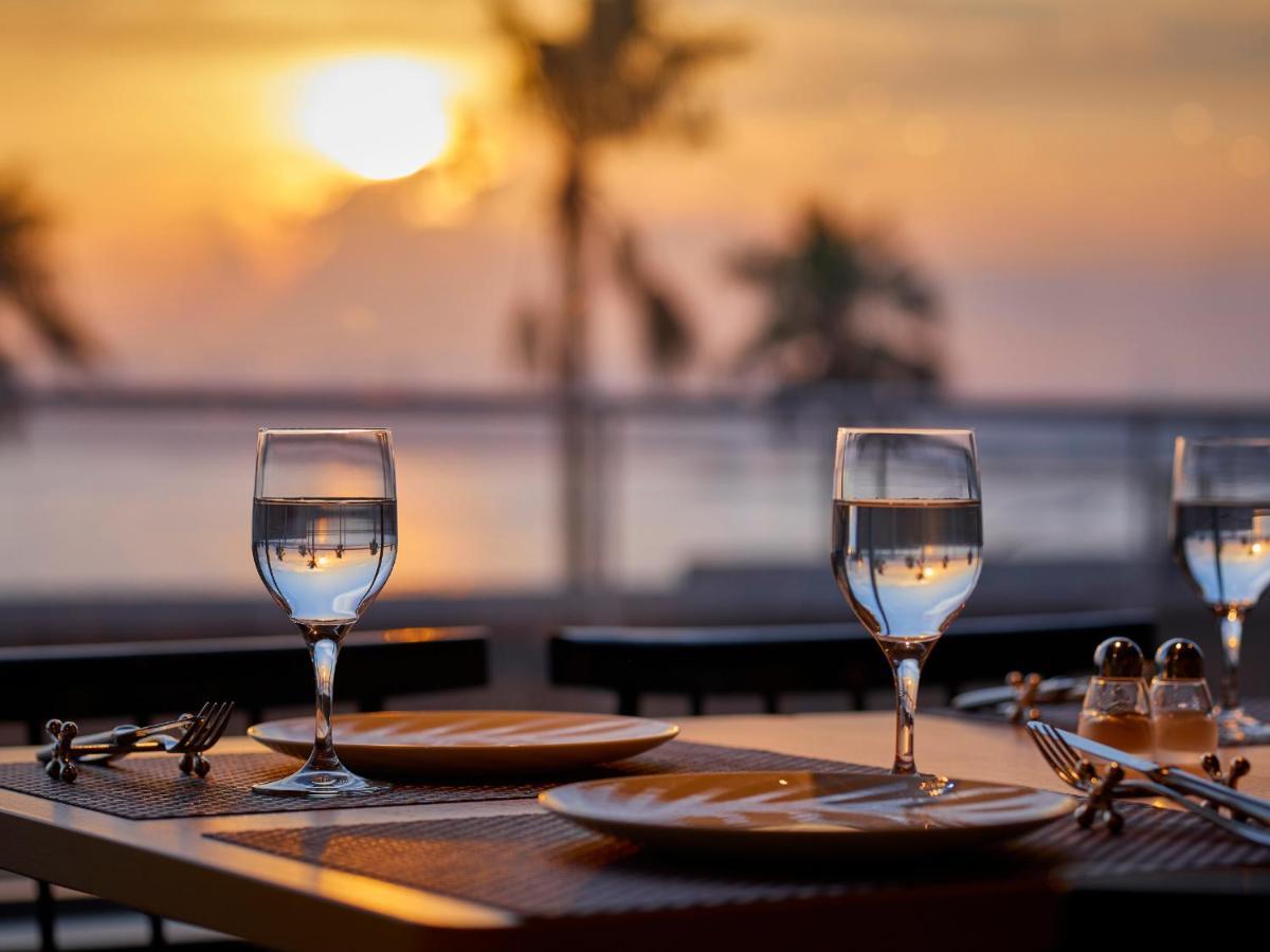Готель Grand Nikko Tokyo Bay Maihama Urayasu Екстер'єр фото The photo depicts a picturesque dining setting at sunset. In the foreground, there are two elegantly arranged tables, each set with plates and glasses filled with water. The glasses are crystal clear, reflecting the warm colors of the sunset. Behind 