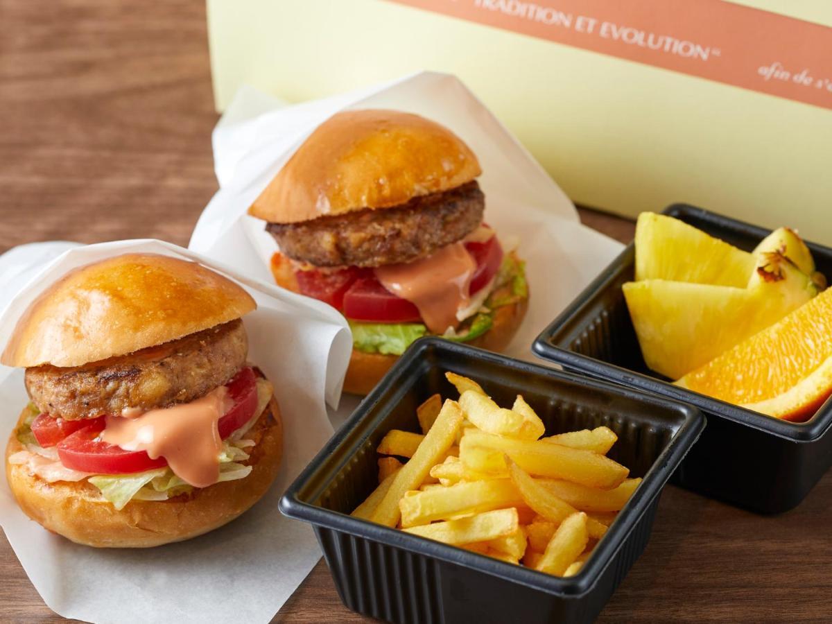 Готель Grand Nikko Tokyo Bay Maihama Urayasu Екстер'єр фото The photo shows two small burgers placed on a white background, each with a golden-brown bun, a fried patty, lettuce, tomato, and a creamy sauce. Alongside the burgers, there are two containers: one holding a serving of french fries and the other con