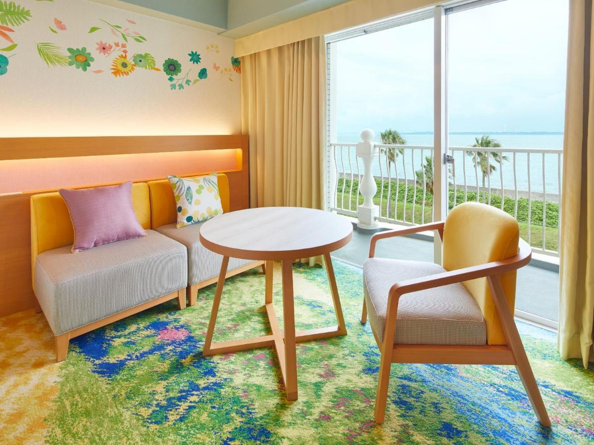 Готель Grand Nikko Tokyo Bay Maihama Urayasu Екстер'єр фото The photo shows a cozy interior space, likely a hotel room or a lounge area. It features a small round table in the center surrounded by comfortable seating. There are two chairs: one is a light wooden frame with a yellow seat, and the other has a mo
