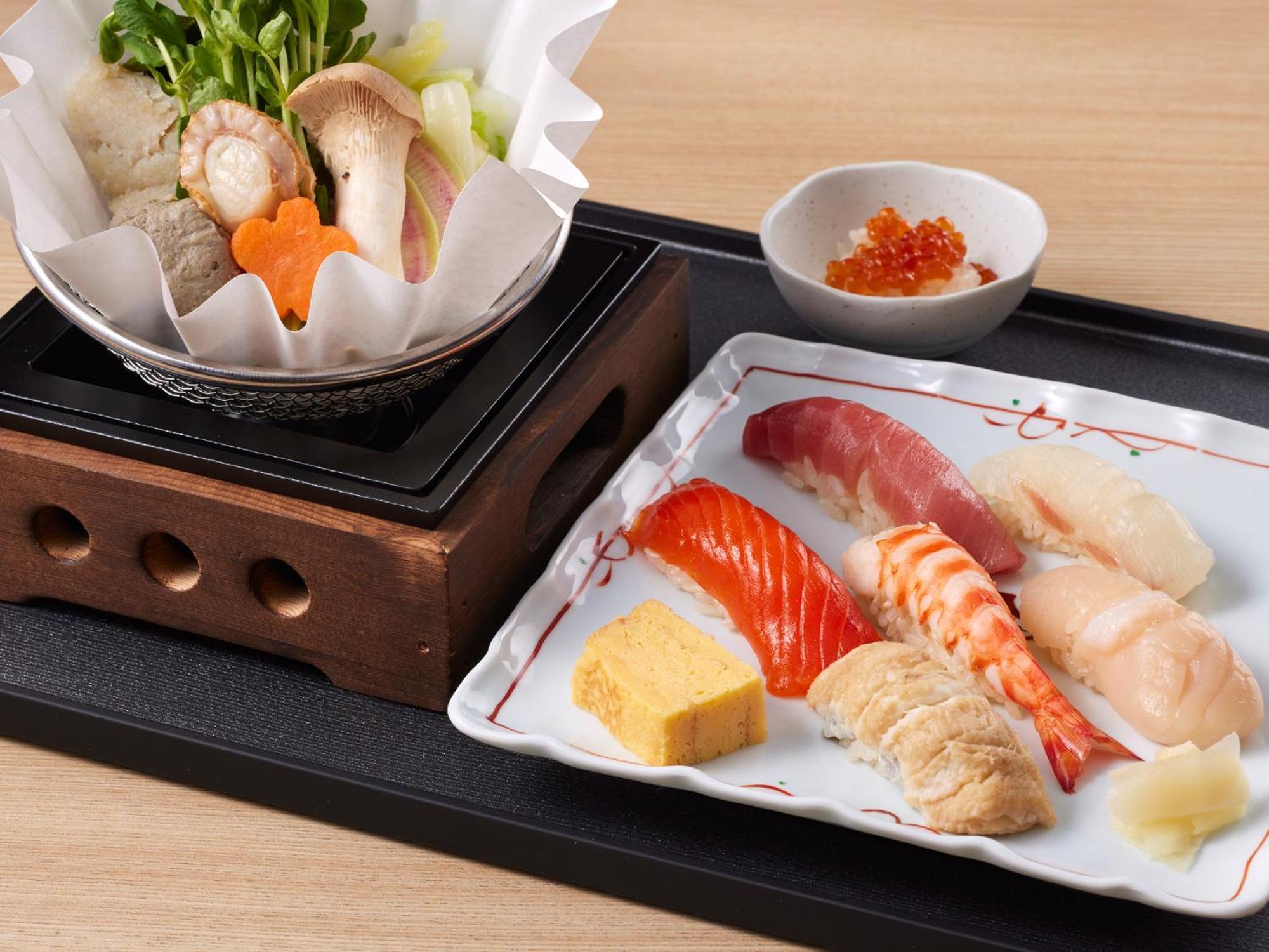 Готель Grand Nikko Tokyo Bay Maihama Urayasu Екстер'єр фото The photo features a Japanese meal presented on a wooden tray. On the left, there is a small pot with a clear broth containing vegetables, mushrooms, and possibly meat, indicated by green herbs and a piece shaped like a flower. On the right, there is