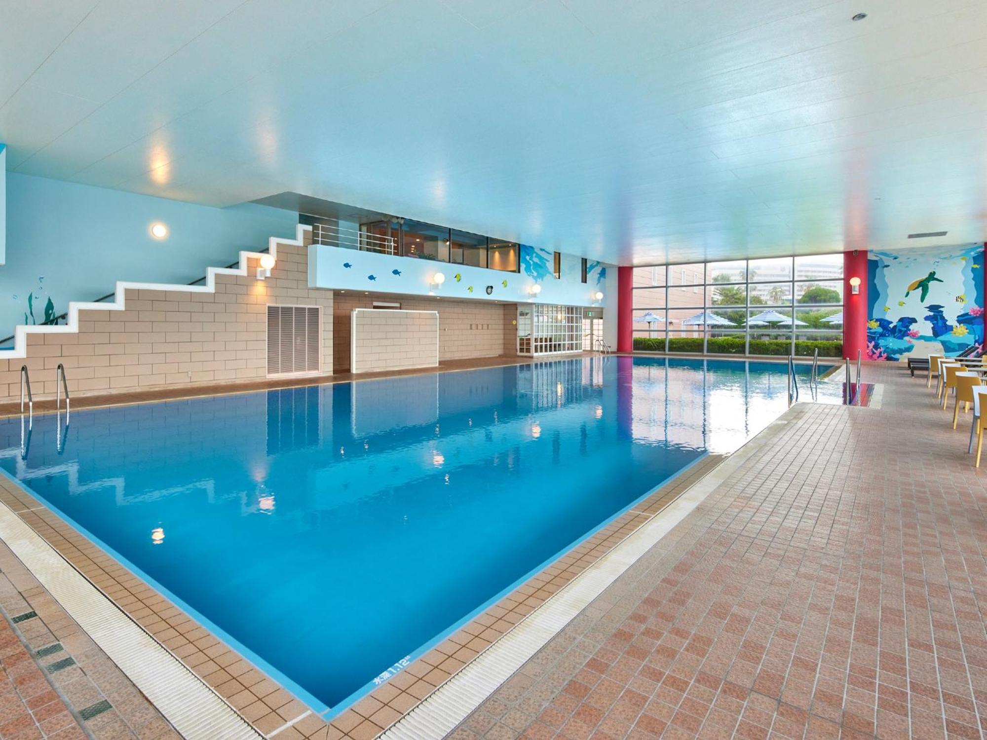 Готель Grand Nikko Tokyo Bay Maihama Urayasu Екстер'єр фото The photo shows an indoor swimming pool area with a spacious design. The pool has a clear blue water surface and is surrounded by a tiled deck. On one side of the pool, there are steps leading into the water, and there are large windows letting in na