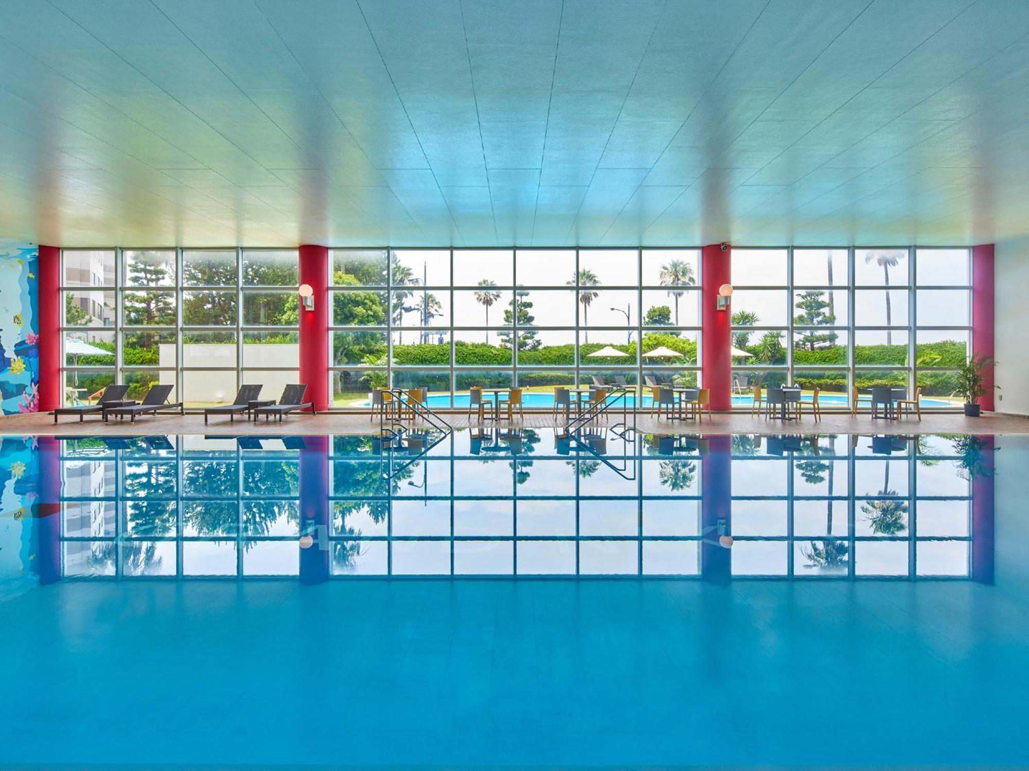 Готель Grand Nikko Tokyo Bay Maihama Urayasu Екстер'єр фото The photo shows an indoor swimming pool with bright blue water. The pool area is spacious, characterized by large windows that allow natural light to flood in, creating a vibrant atmosphere. The walls are painted in a soft color, with accents of red.